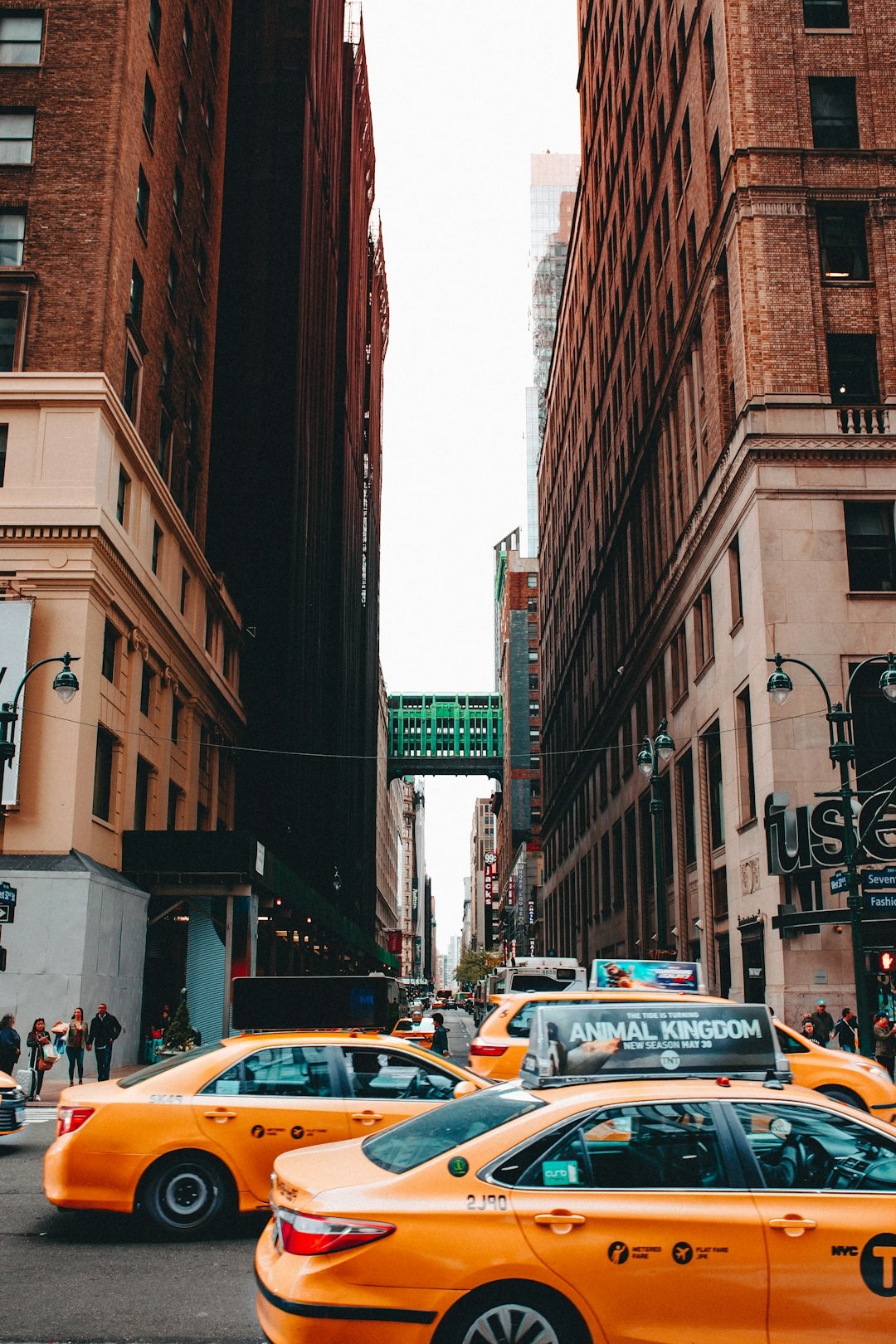 Street view with yellow taxis and tall buildings in a busy urban area.